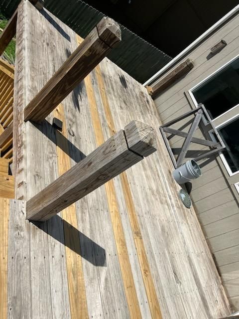 Wooden deck with two upright beams, next to a light fixture and building.