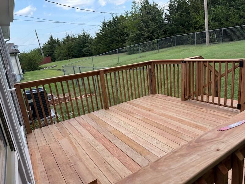Exterior view of a two-story house with gray siding, a deck, and a sliding glass door.