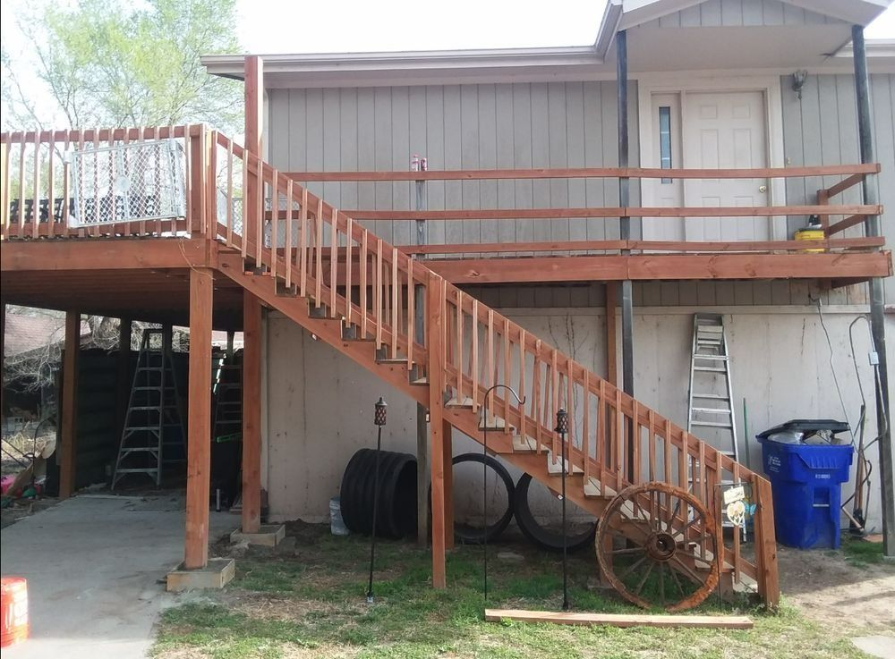 Wooden staircase leads to a deck connected to a light beige two-story building.