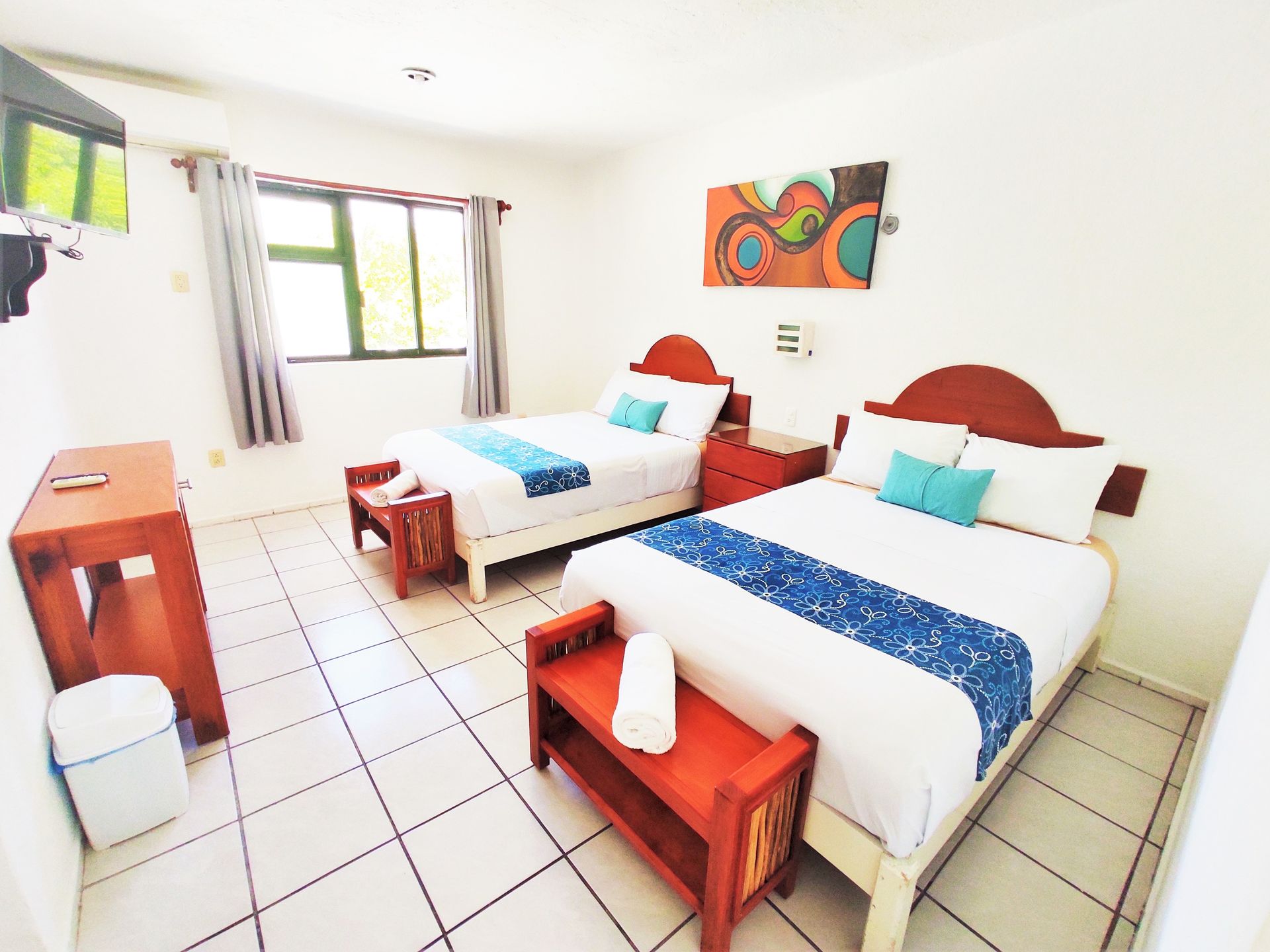 Una habitación de hotel con dos camas y un banco.