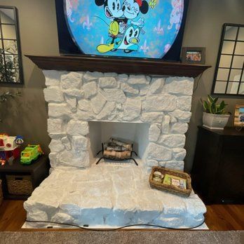A living room with a stone fireplace and a television above it.