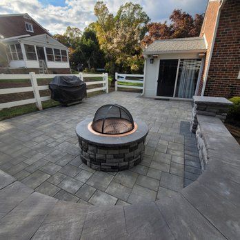 A fire pit is sitting on a patio next to a house.