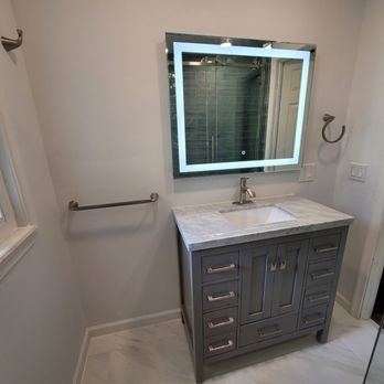 A bathroom with a sink , mirror and towel rack.