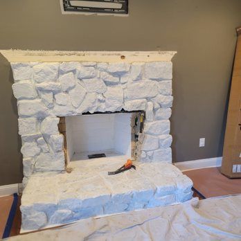 A stone fireplace is being built in a living room