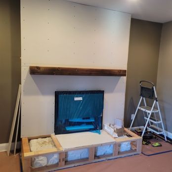 A fireplace is being built in a living room with a wooden mantle.