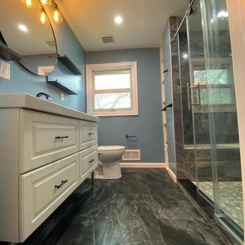 A bathroom with a toilet , sink , mirror and shower.