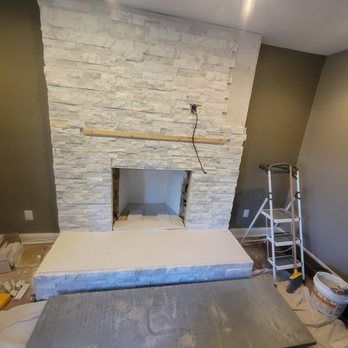 A white brick fireplace is being built in a living room.