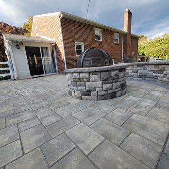 A fire pit is sitting on a patio in front of a brick house.