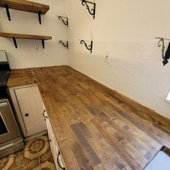 A kitchen with a wooden counter top and white cabinets.