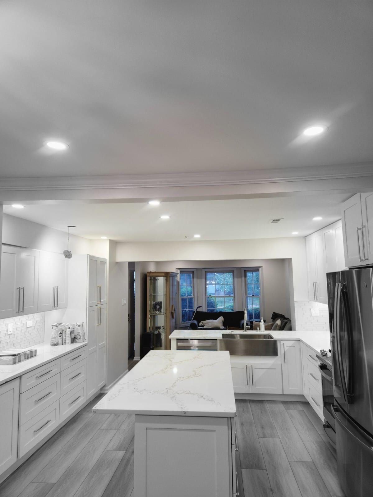 A kitchen with white cabinets , stainless steel appliances , and a large island.