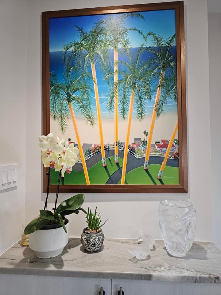 A painting of palm trees is hanging on a wall above a counter.