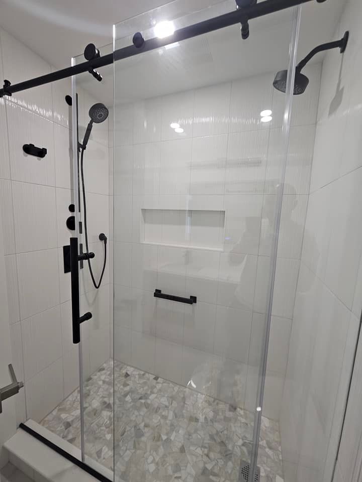 A bathroom with a sliding glass shower door and a shower head.