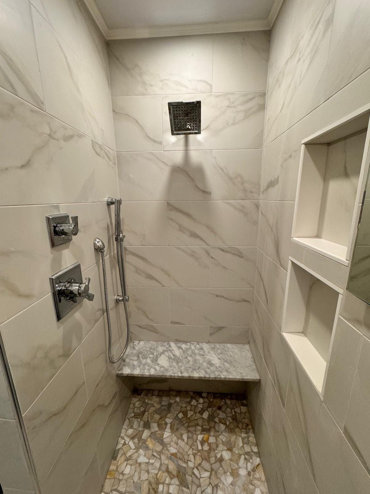 A bathroom with a walk in shower and a bench.