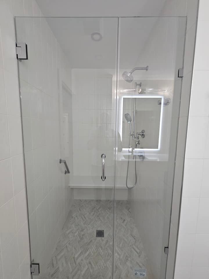 A bathroom with a glass shower door and a mirror.