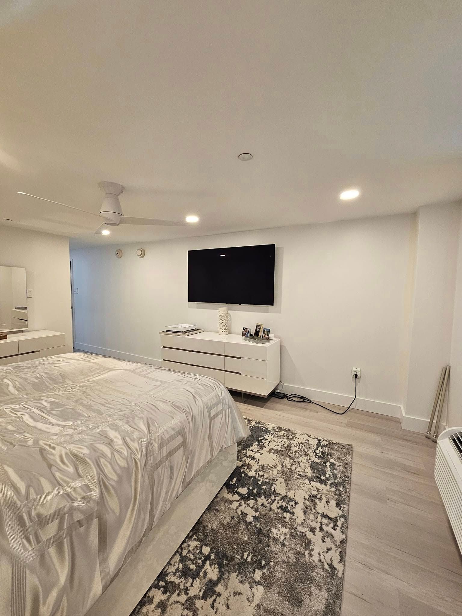 A bedroom with a bed , dresser , television and rug.