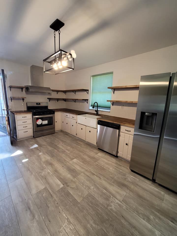 A kitchen with stainless steel appliances and wooden floors.