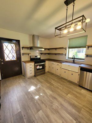 A kitchen with stainless steel appliances and wooden floors.