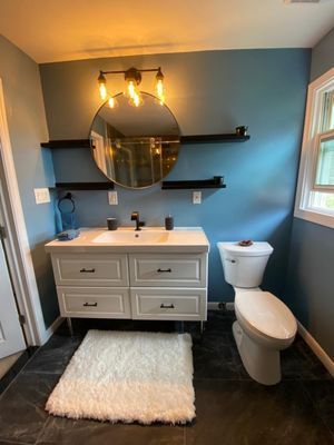A bathroom with a toilet , sink and mirror.