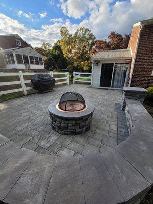 A fire pit is sitting on top of a patio next to a house.