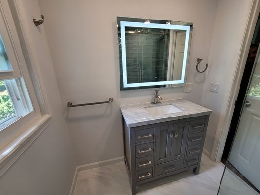 A bathroom with a sink , mirror and drawers.