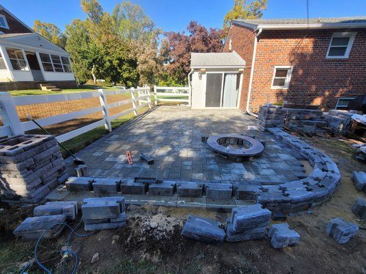 A fire pit is being built in the backyard of a house.