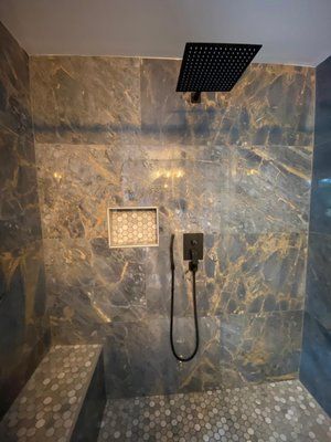 A walk in shower with a bench and a shower head.