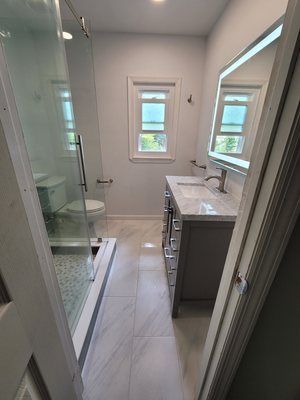 A bathroom with a sink , toilet , shower and mirror.