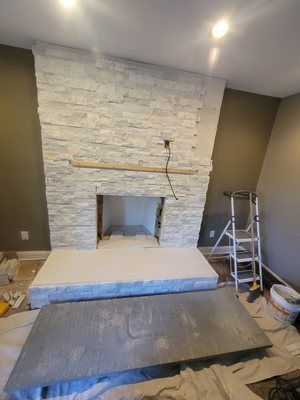 A white brick fireplace is being built in a living room.