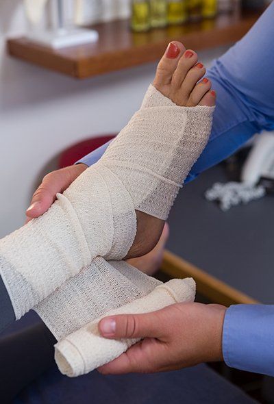 Doctor Putting Bandage on Injured Feet — Fresno, CA — Dr. Brent L Woodbury DPM