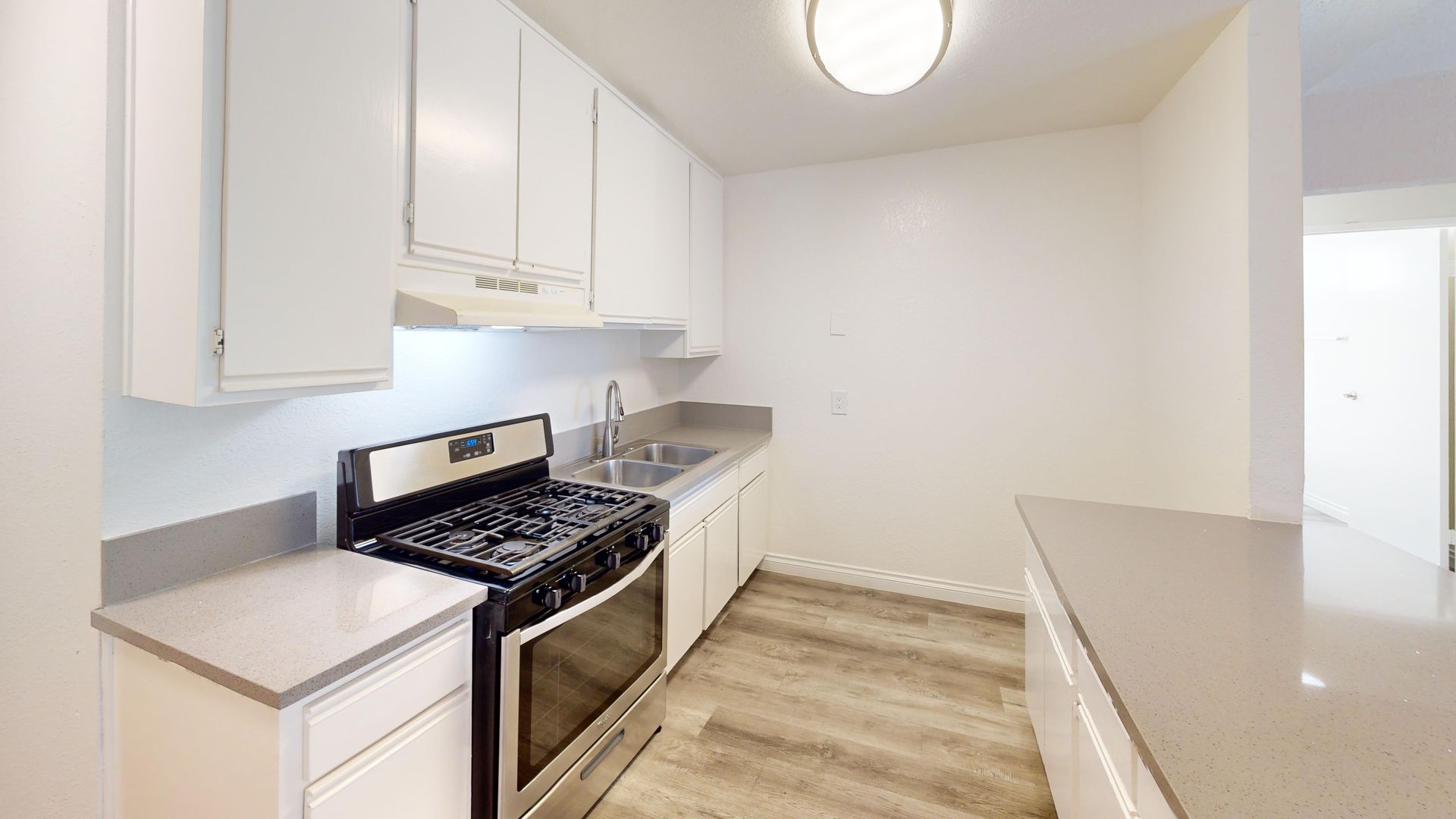 Small kitchen with white cabinets, stainless steel stove, and light gray countertops.