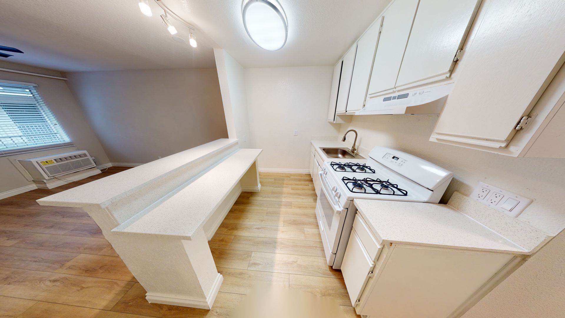 White kitchen with stove, cabinets, and a long island.
