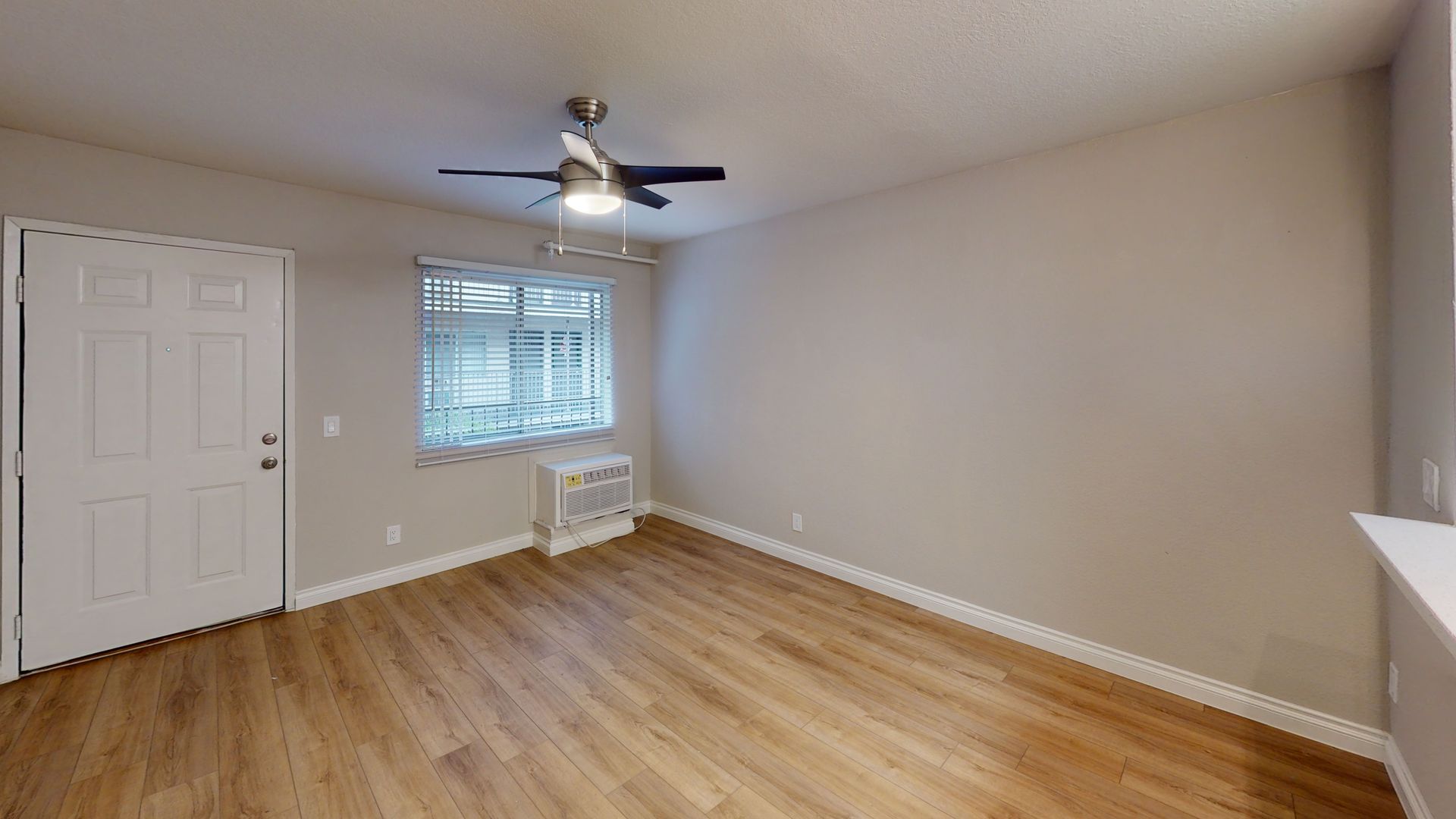 Empty room with wood floors, a window, and a ceiling fan.