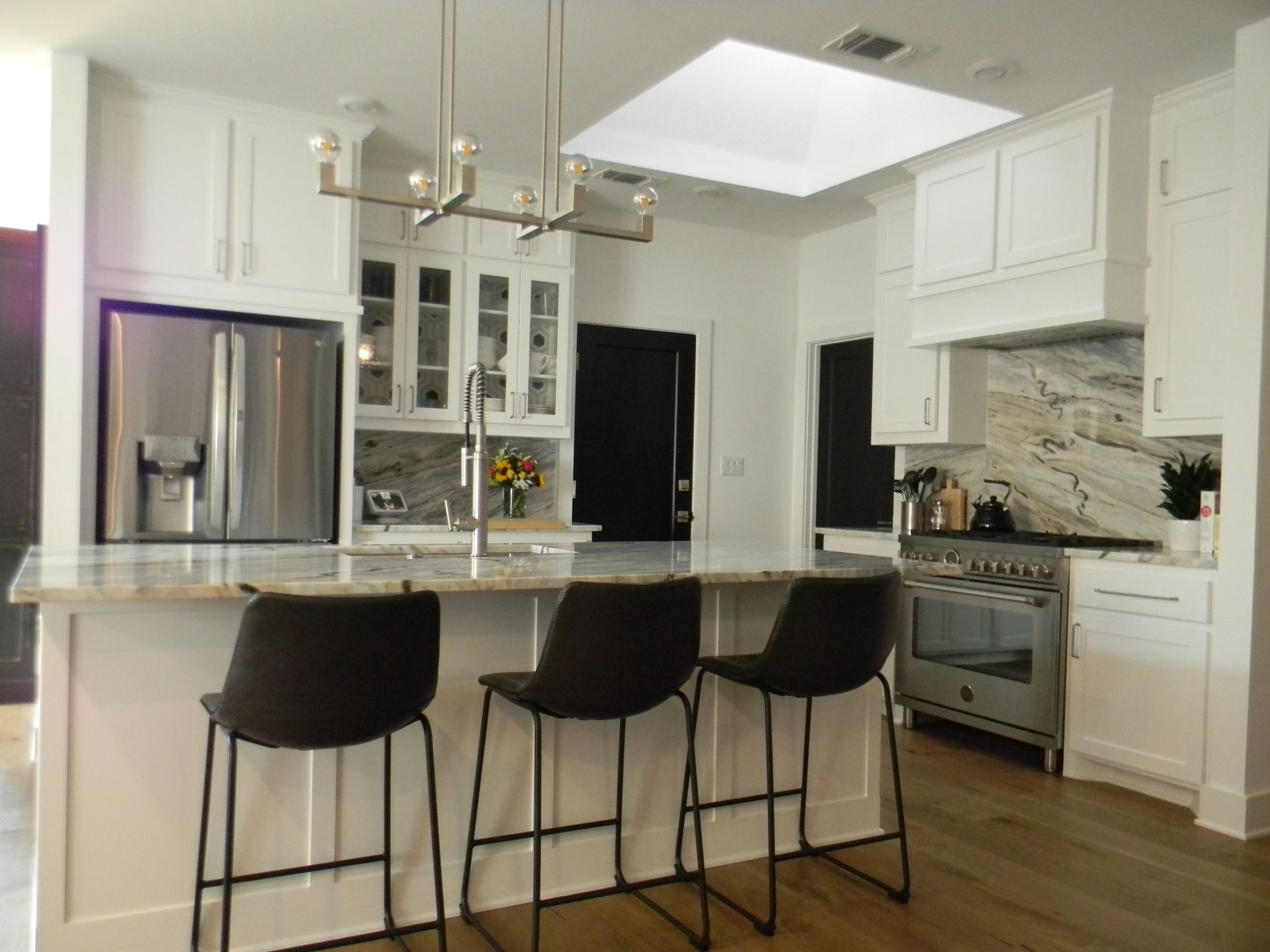 A kitchen with white cabinets and stools and a stove