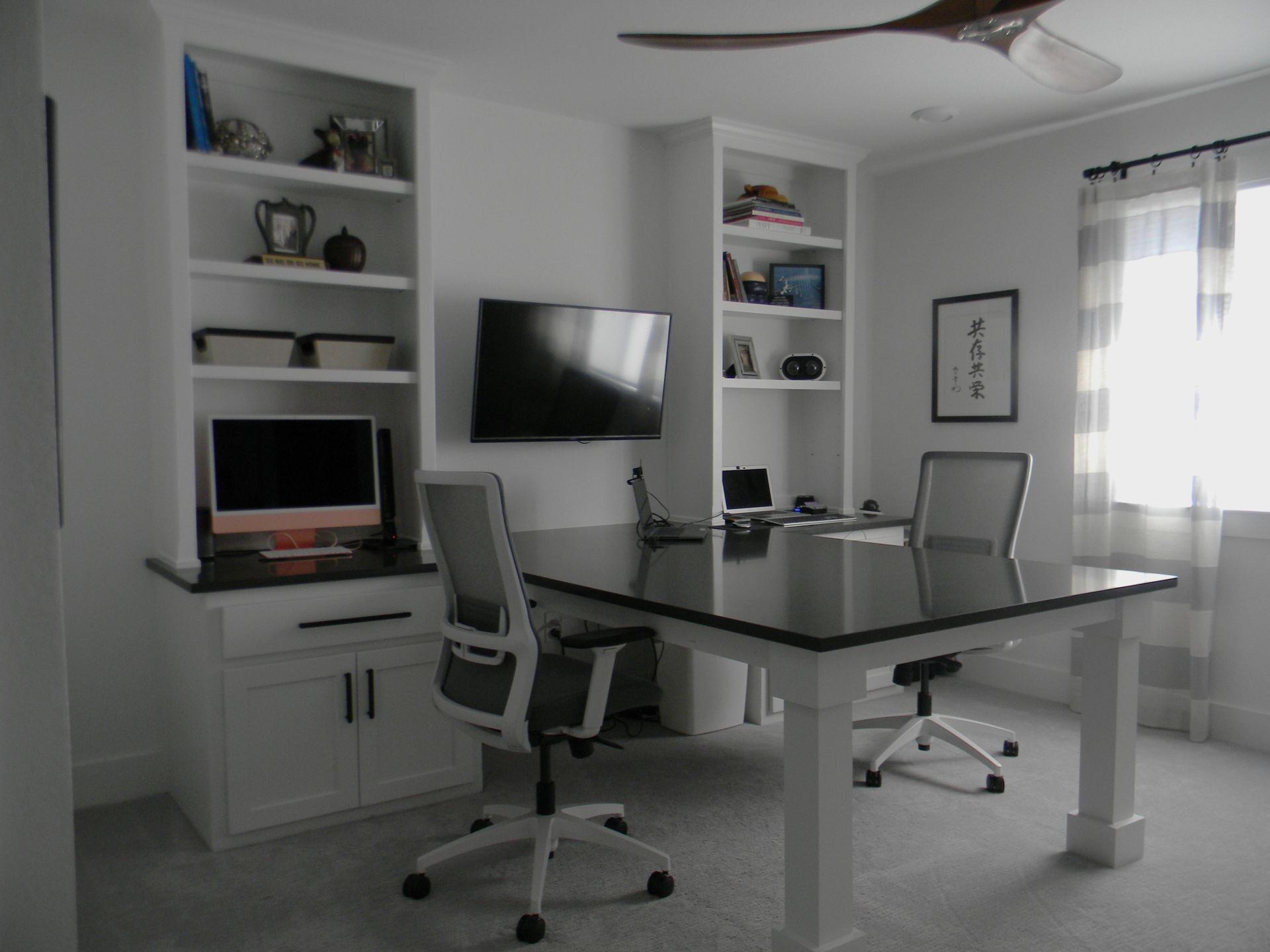 A home office with a desk and chairs and a flat screen tv