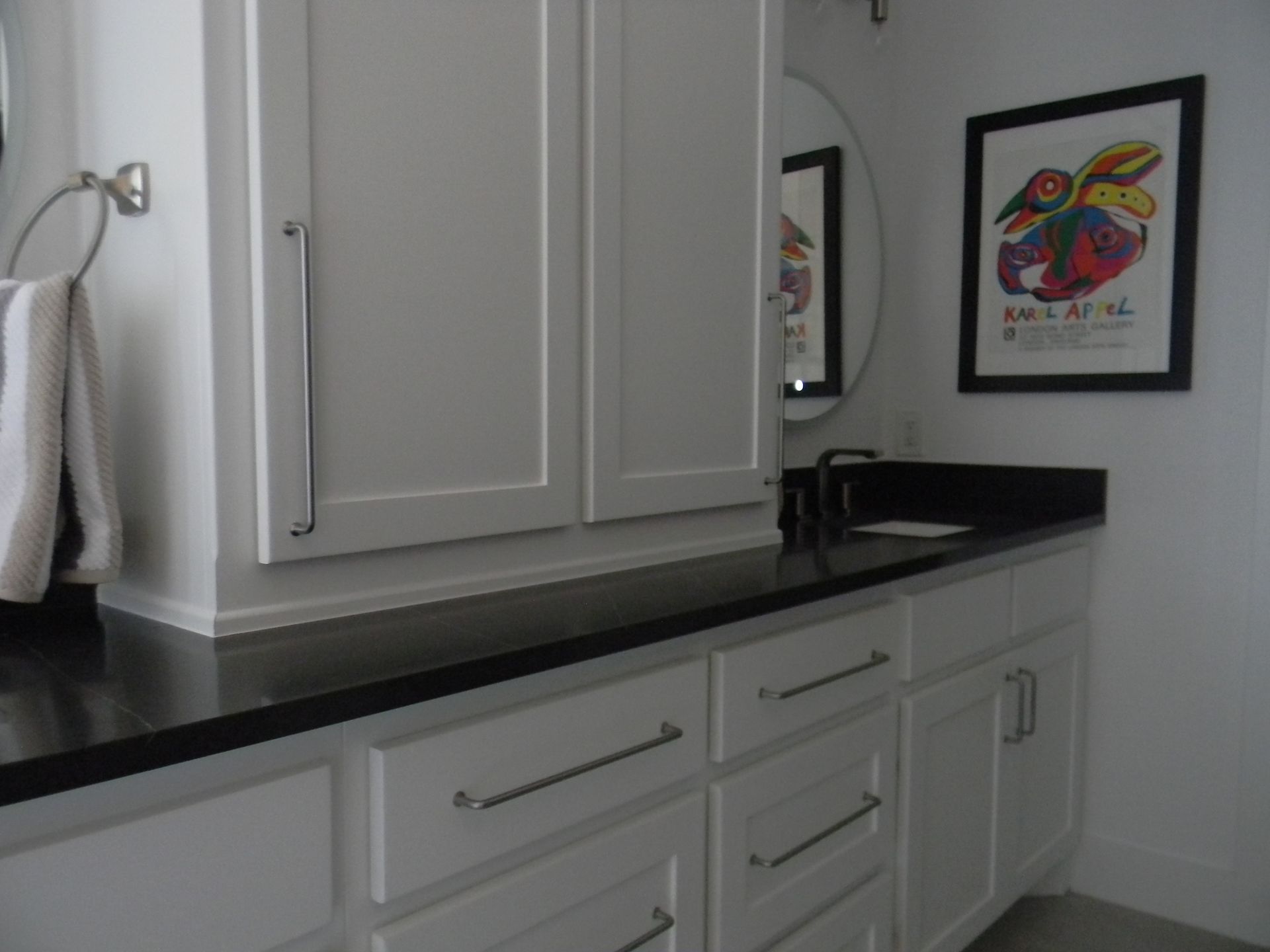 A bathroom with white cabinets and black counter tops