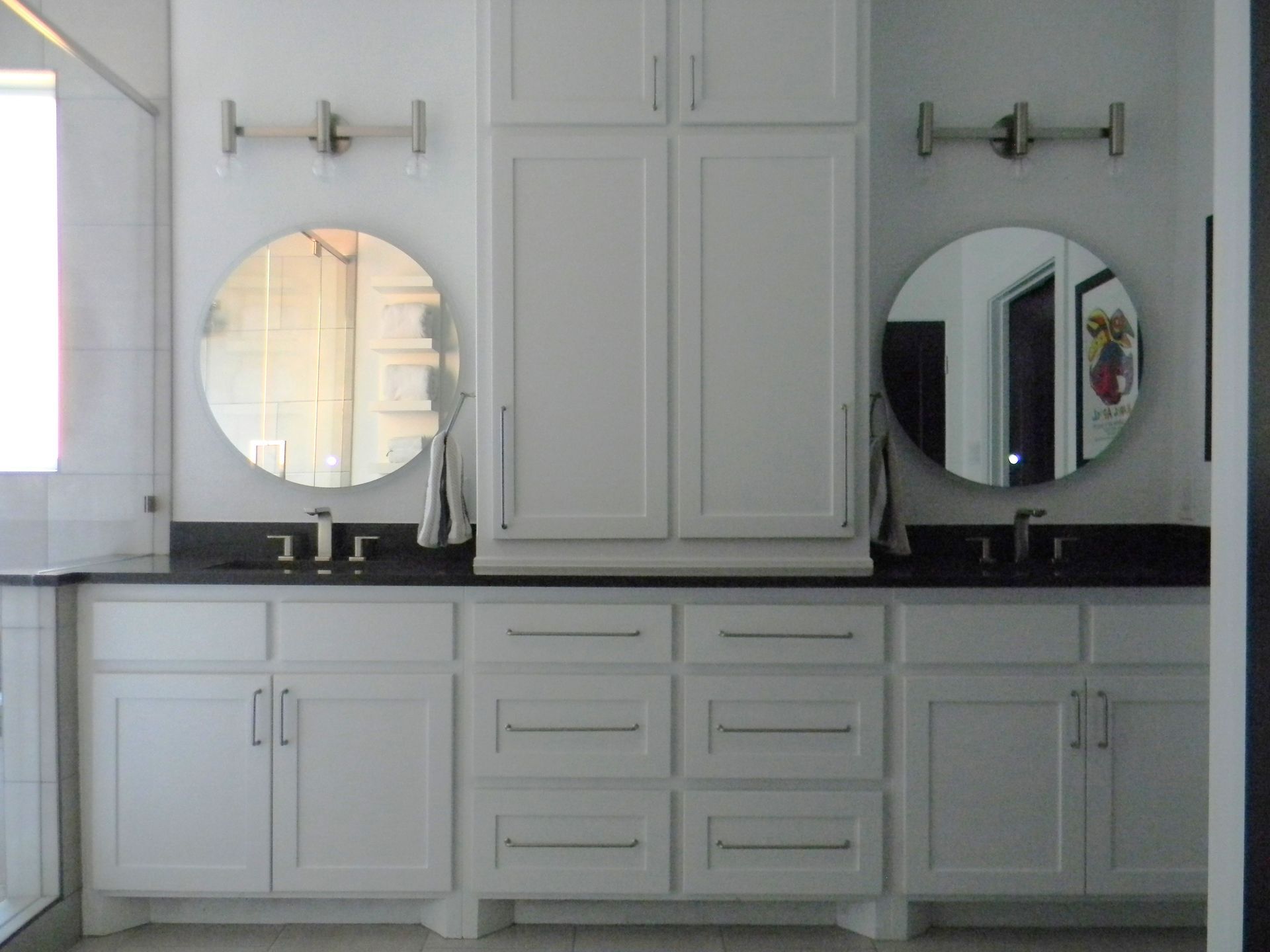 A bathroom with two sinks and two round mirrors