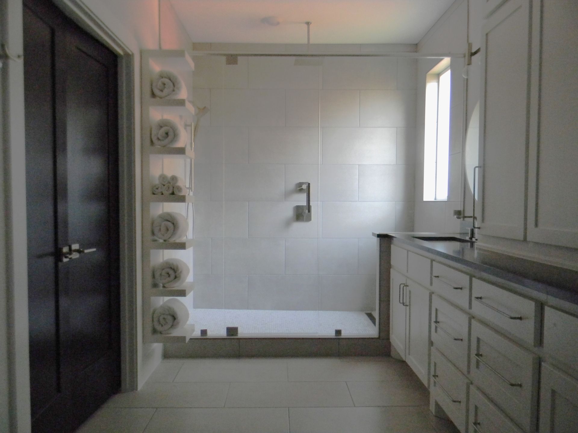 A bathroom with white cabinets and a walk in shower