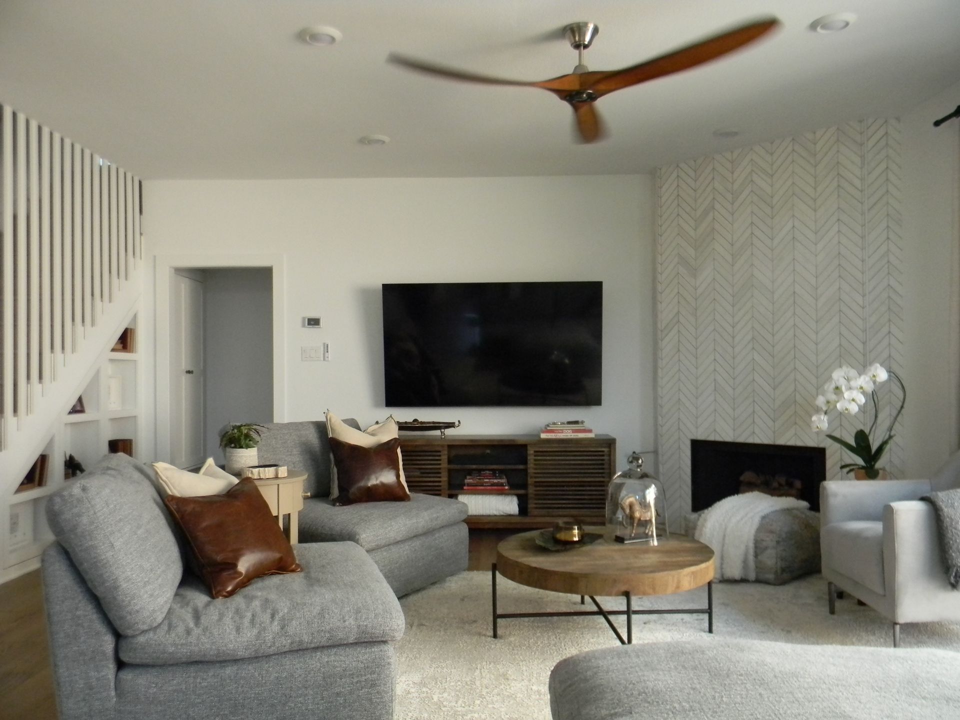 A living room with a ceiling fan and a flat screen tv