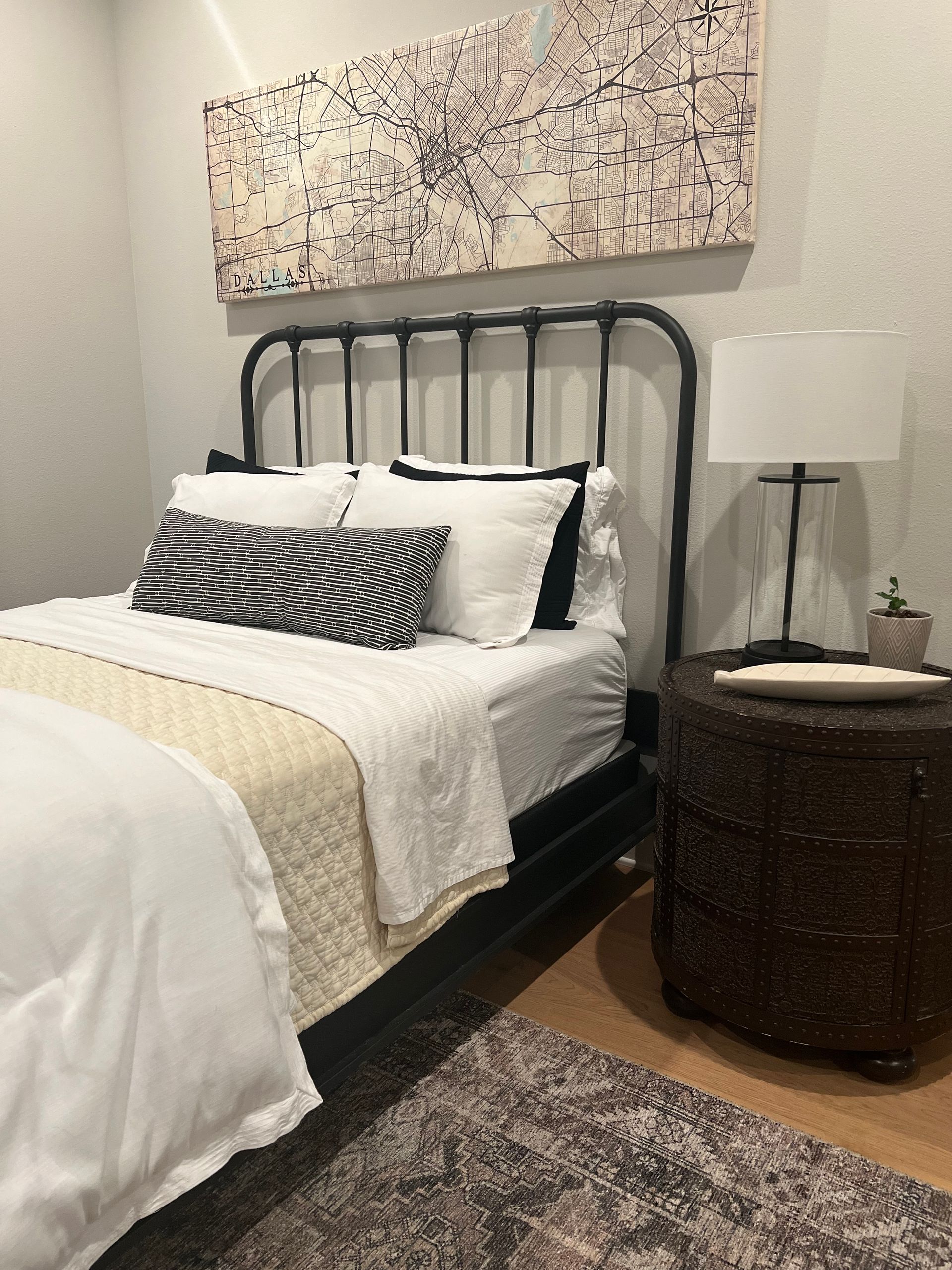 A bedroom with a bed , nightstand , lamp and painting on the wall.