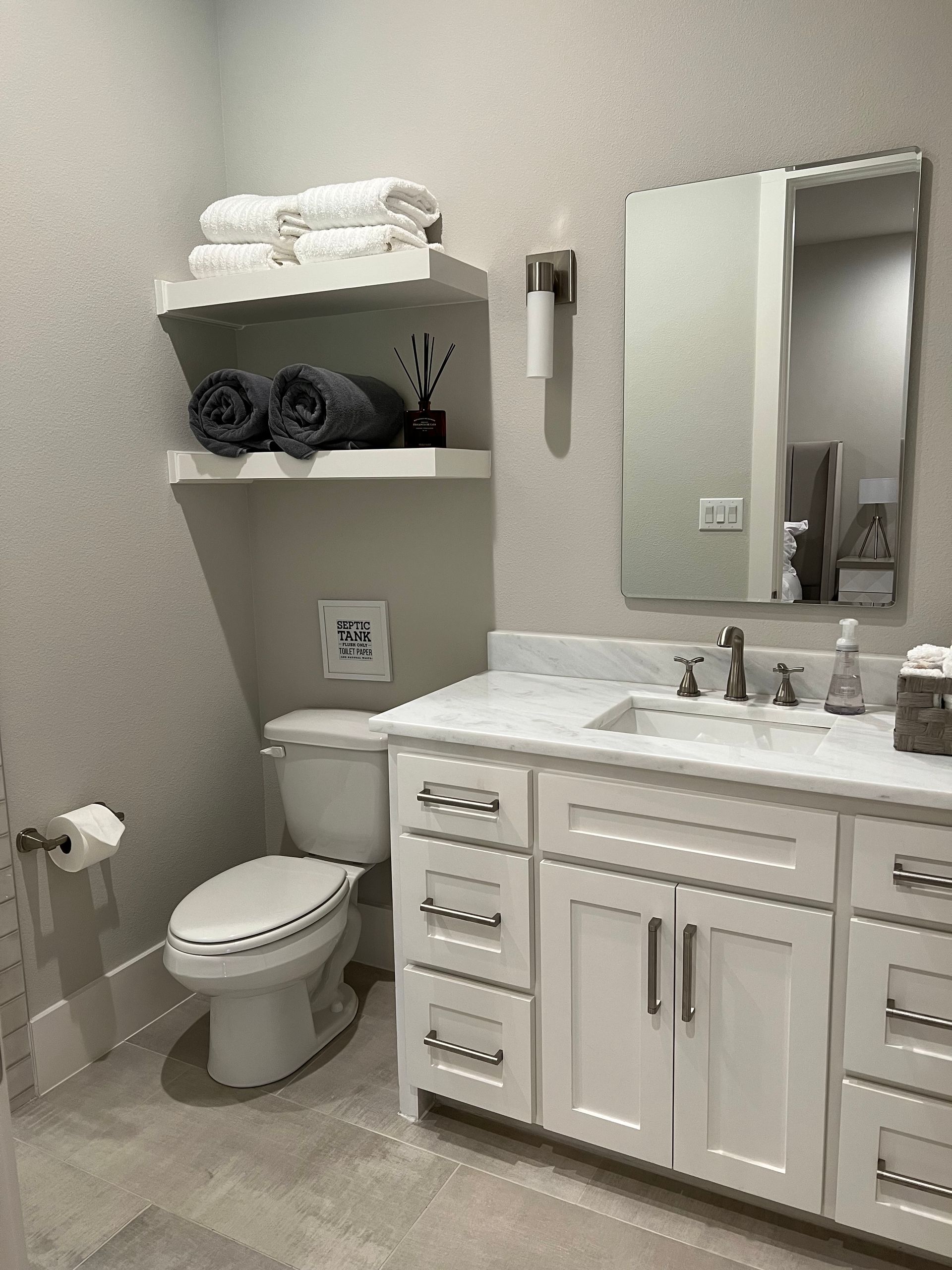 A bathroom with a toilet , sink and mirror.
