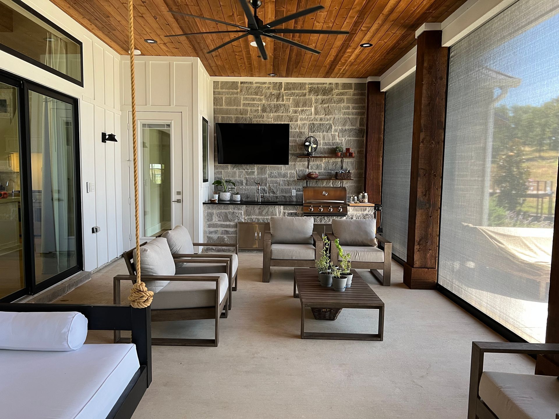 A living room with a ceiling fan , chairs , a table and a television.