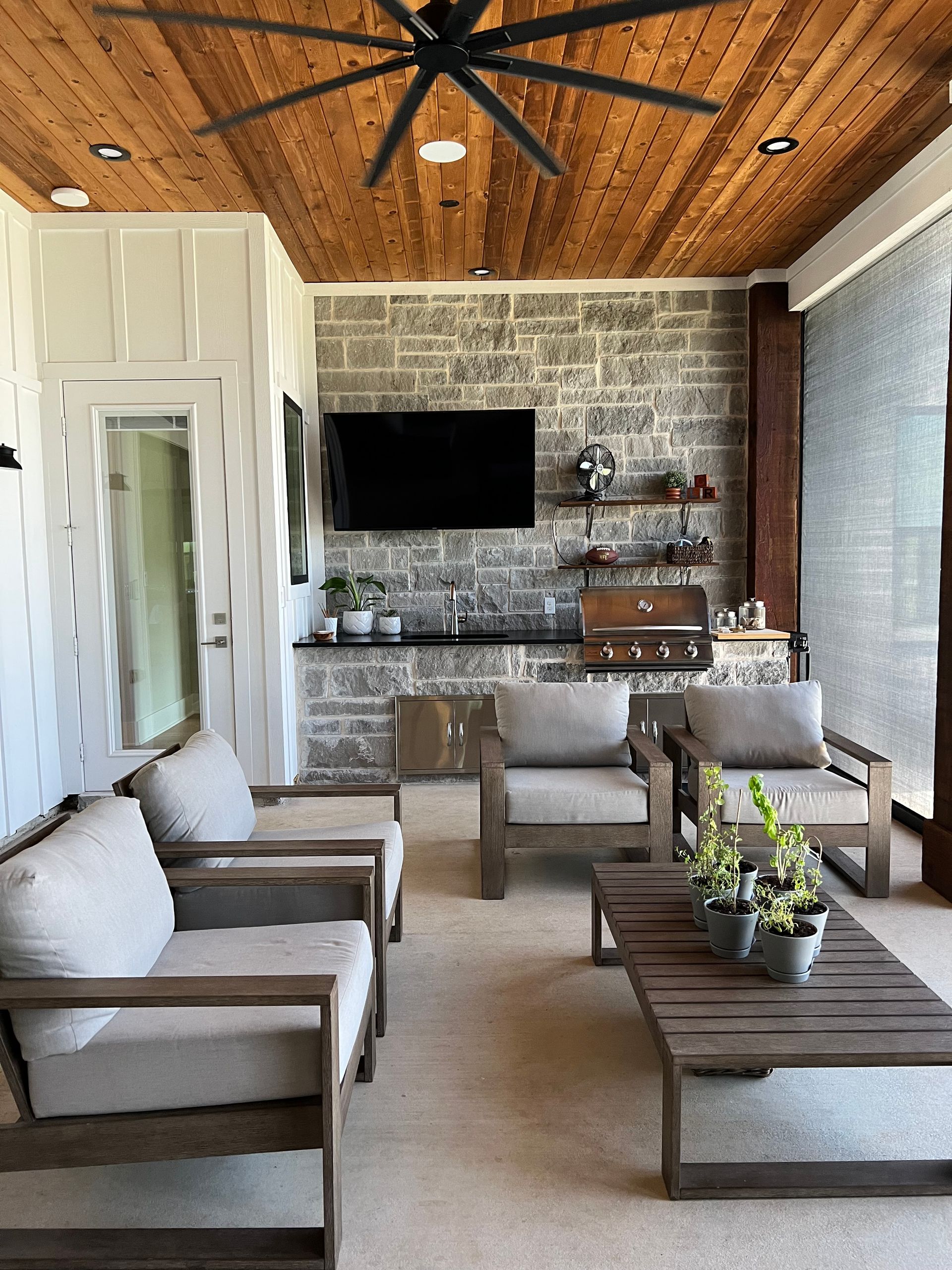 A living room with chairs , a table , a television and a ceiling fan.