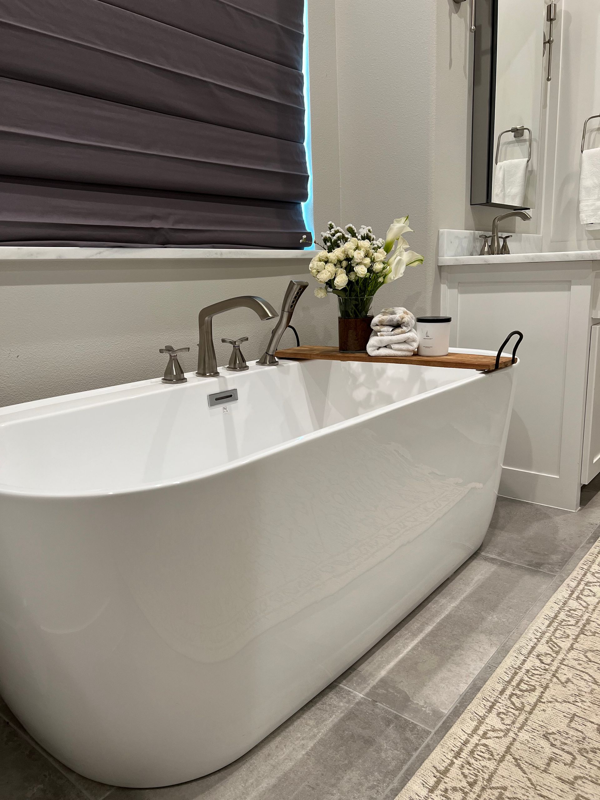 A white bathtub in a bathroom next to a window.
