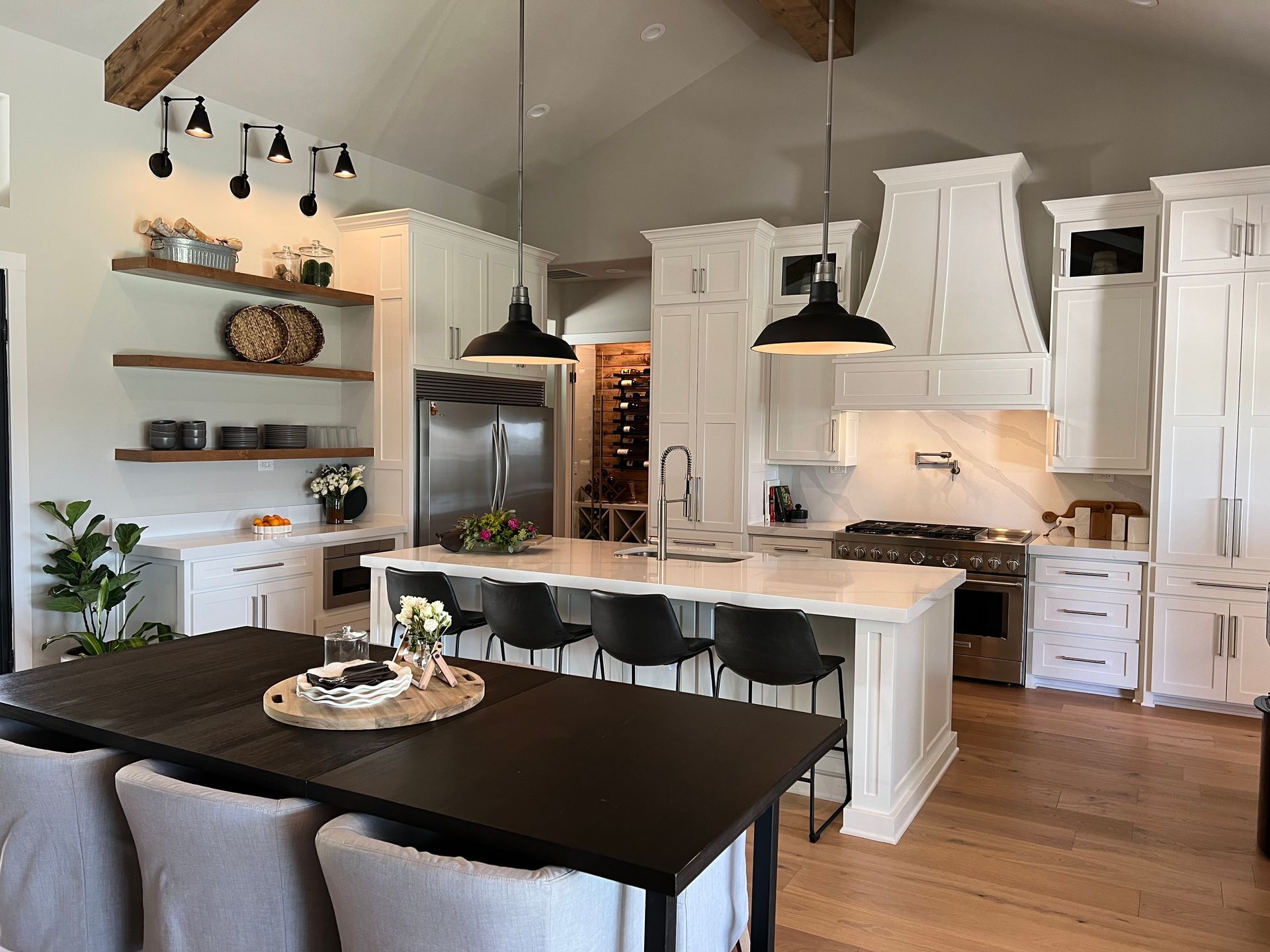 A kitchen with white cabinets , a large island , a table and chairs.