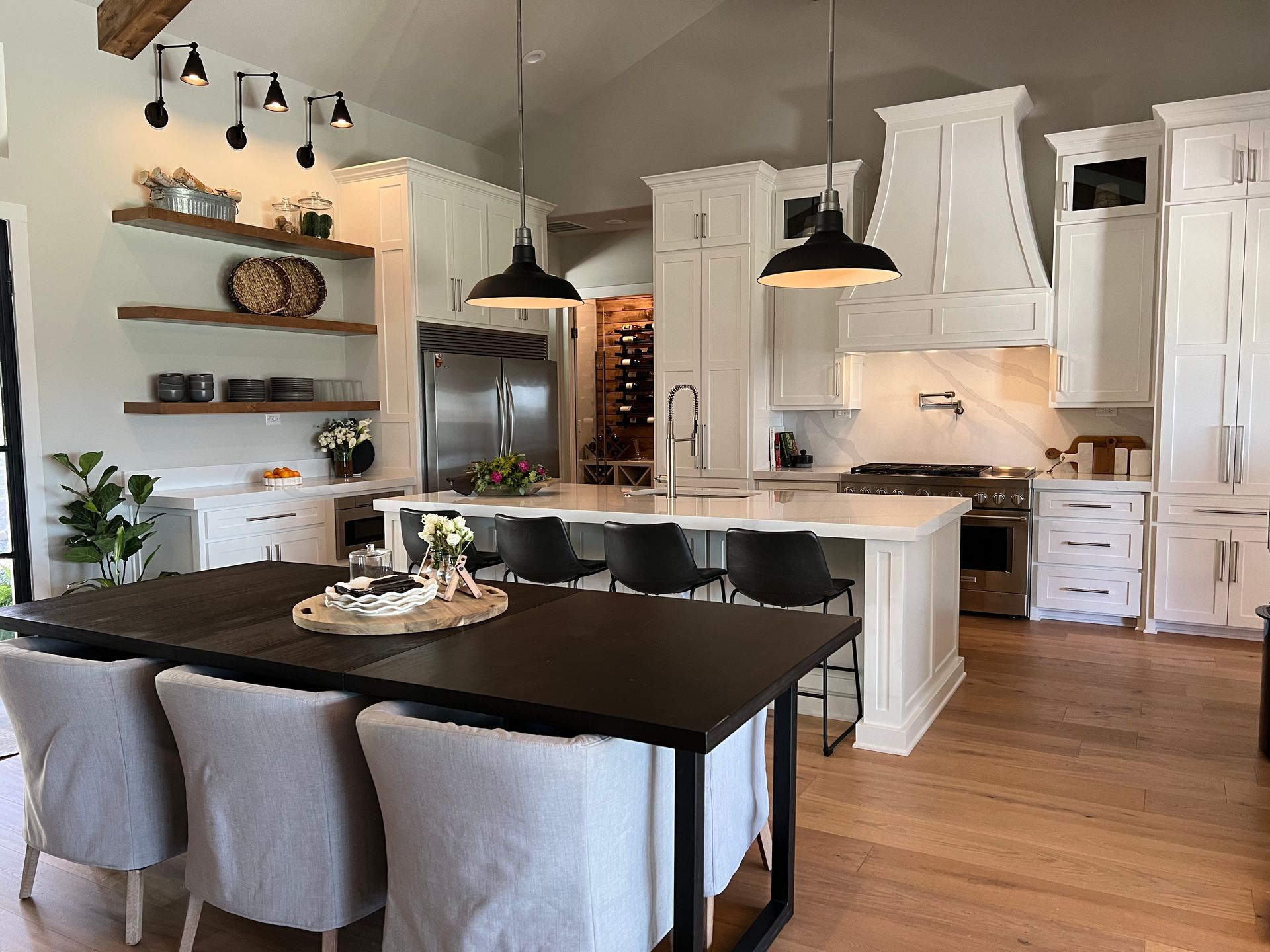 A kitchen with white cabinets , stainless steel appliances , a table and chairs.