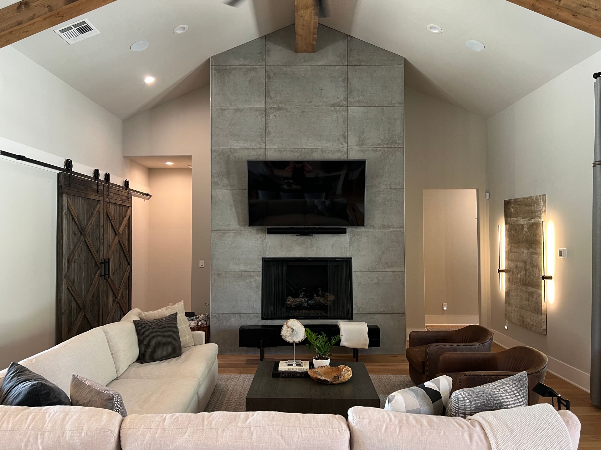 A living room with a couch , chairs , fireplace and television.