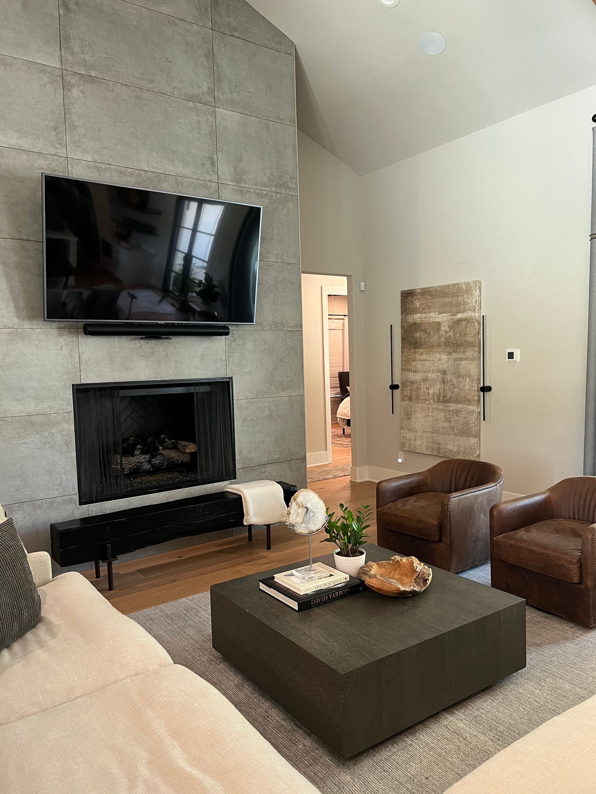 A living room with a fireplace , couch , chairs , coffee table and television.