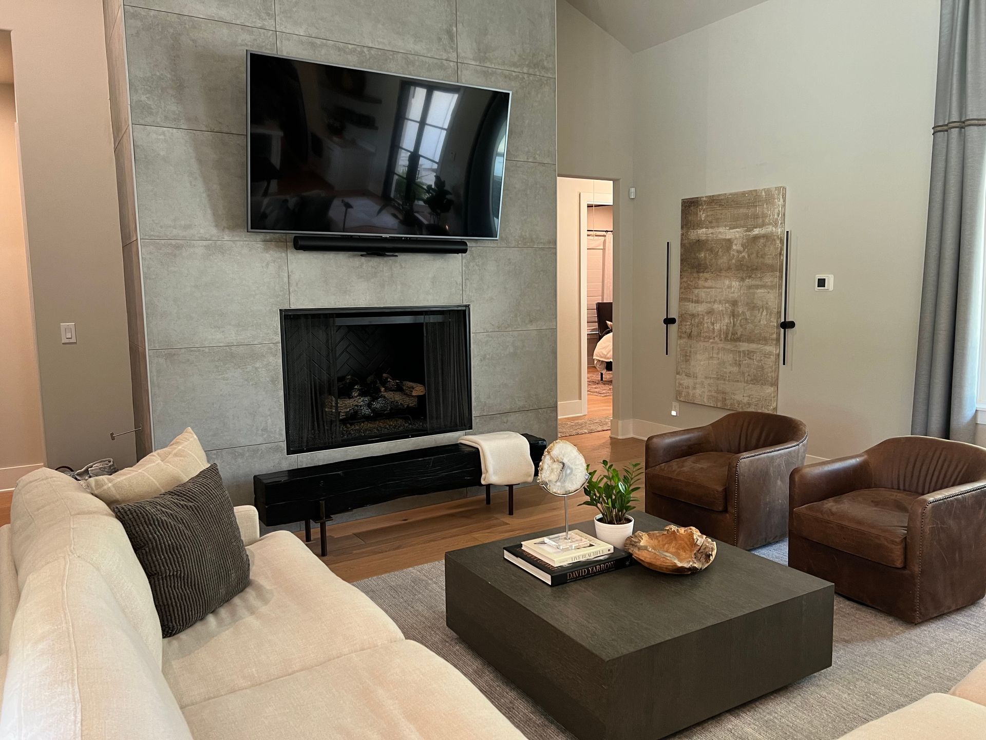 A living room with a fireplace , couch , chairs and a flat screen tv.