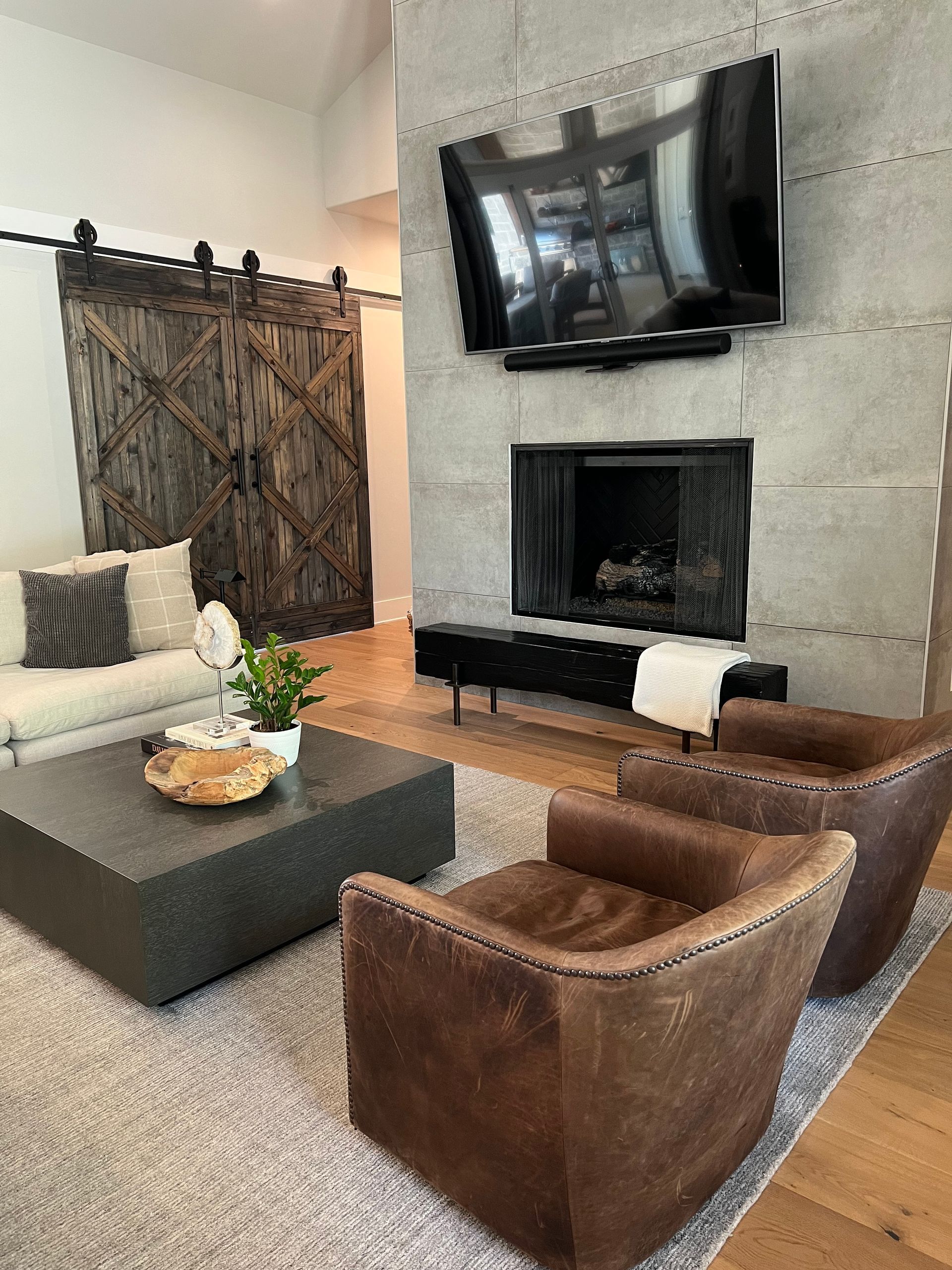 A living room with a couch , two chairs , a coffee table and a fireplace.