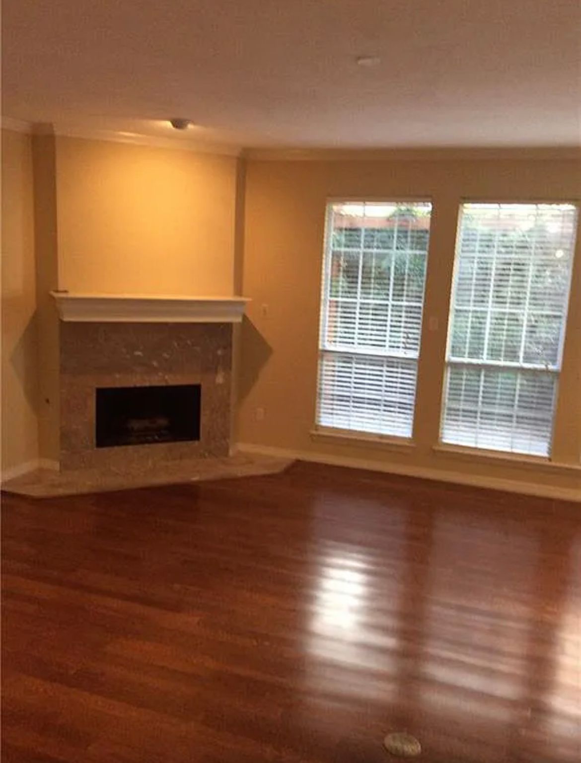 An empty living room with a fireplace and windows